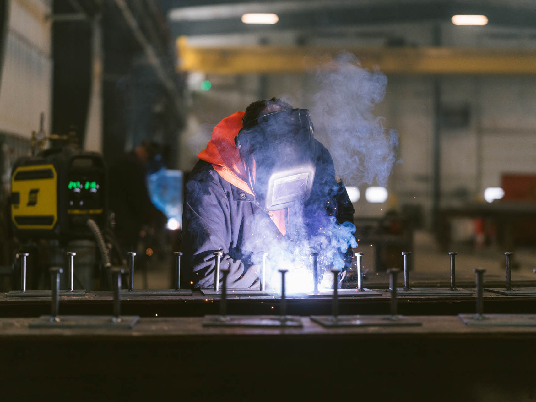 Man in safety gear welding steel in a shop
